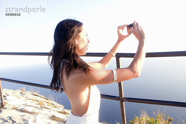 Junge Frau fotografiert Meer auf Smartphone  Marseille  Frankreich