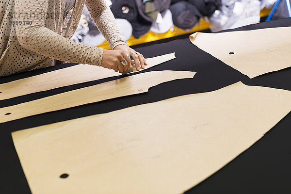 Hände von reifer Schneiderin kreidende Form auf Textil auf Arbeitstisch
