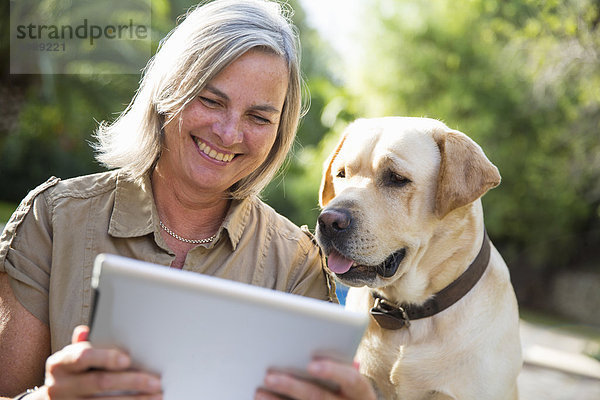 Frau und Hund beim Betrachten des digitalen Tabletts