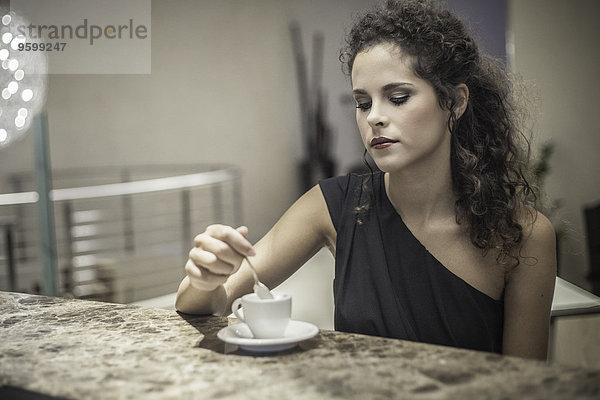 Junge Frau beim Rühren von Kaffee