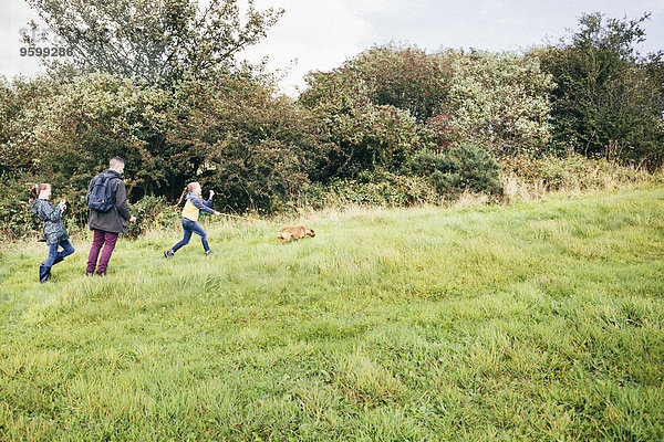 Vater und zwei Mädchen gehender Hund im Feld