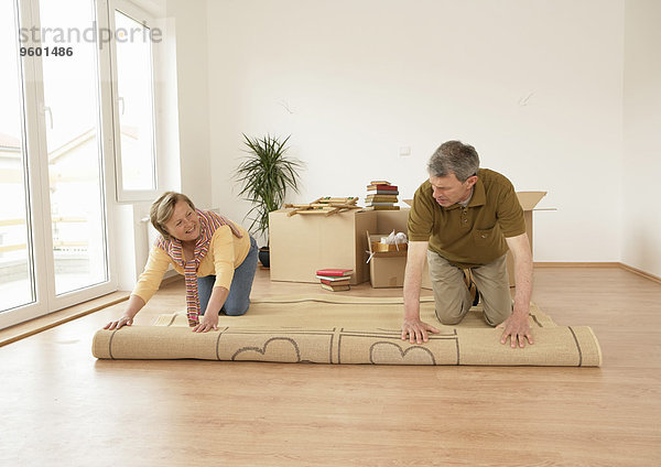 Älteres Paar beim Umzug  Teppich ausrollen