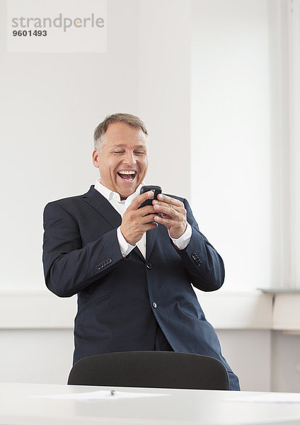 Mann schaut auf sein Handy und lacht schallend