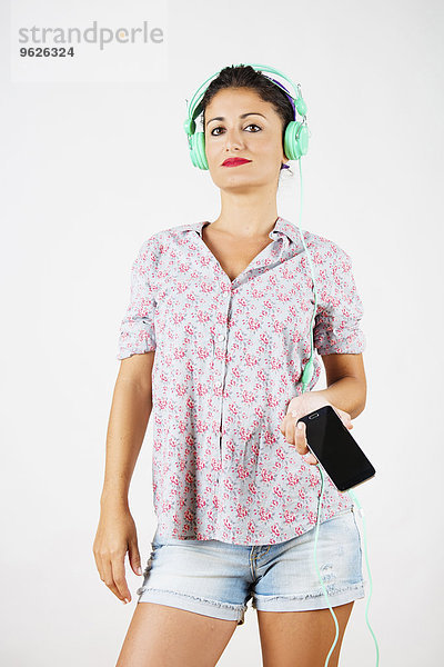 Porträt einer Frau mit Smartphone und Kopfhörer beim Musikhören