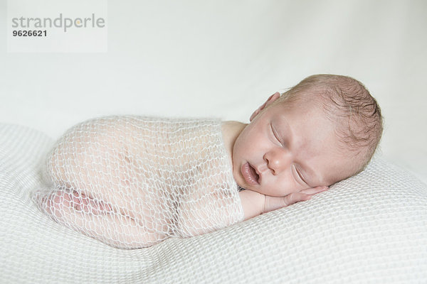 Porträt eines schlafenden Neugeborenen auf weißer Decke