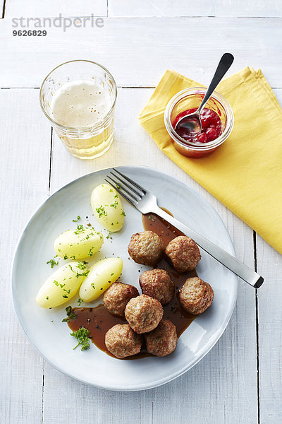 Koettbullar  schwedische Fleischbällchen mit Kartoffeln und Sauce auf dem Teller  Preiselbeeren