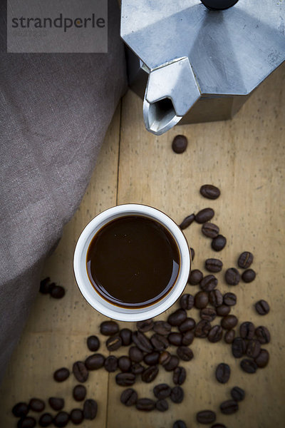 Tasse schwarzer Kaffee  Tuch  Espressodose und Kaffeebohnen