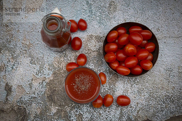 Glas und Flasche Tomatensaft und Tomaten
