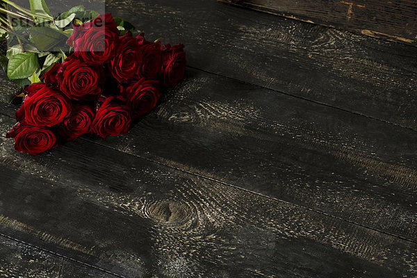 Rote Rosen auf dunklem Holz