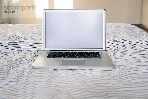Laptop auf dem Bett stehend