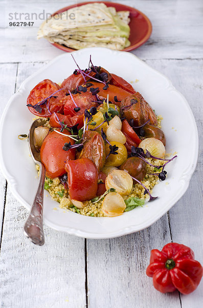 Couscous-Salat mit gedünsteten Tomaten  Knoblauch und Kresse auf dem Teller