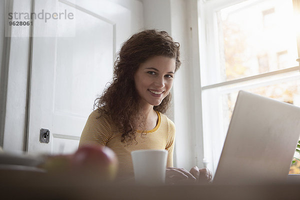 Lächelnde junge Frau zu Hause mit Laptop