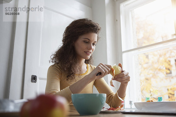 Junge Frau beim Schälen eines Apfels
