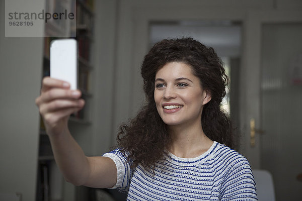 Junge Frau zu Hause mit einem Selfie