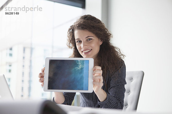 Porträt einer lächelnden jungen Frau am Schreibtisch mit digitalem Tablett
