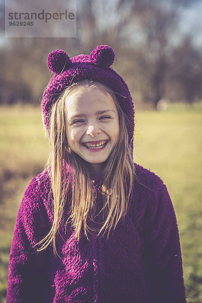 Porträt des lachenden kleinen Mädchens in lila Kapuzenjacke
