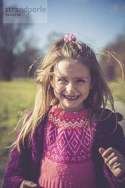 Porträt des lächelnden kleinen Mädchens mit rosa Strickpullover