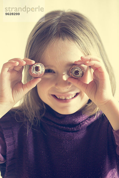Lächelndes kleines Mädchen mit zwei Litschis vor den Augen