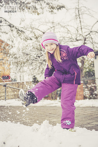 Lächelndes kleines Mädchen tritt in den Schnee