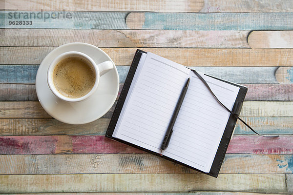 Tasse Kaffee und geöffnetes Notizbuch