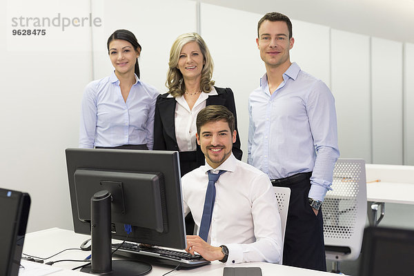 Porträt von lächelnden Geschäftsleuten am Schreibtisch im Büro