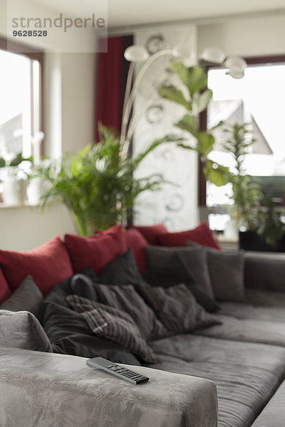 Wohnzimmer mit grauer Couch und Fernbedienung an der Armlehne