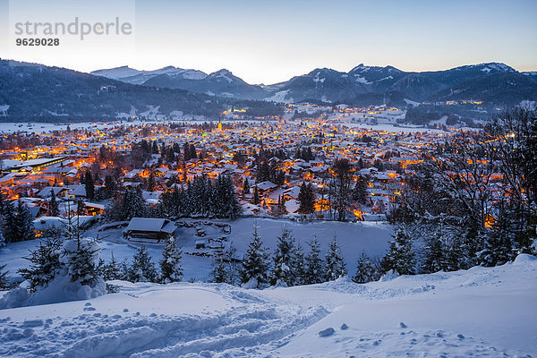 Deutschland  Bayern  Blick auf das schneebedeckte beleuchtete Oberstdorf vor den Allgäuer Alpen