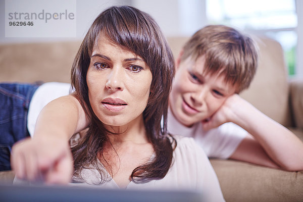 Mutter und Sohn zu Hause mit Blick auf den Laptop