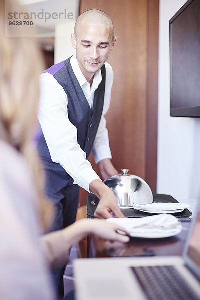 Zimmerservice für Geschäftsfrau am Laptop im Hotelzimmer