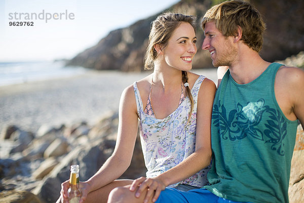 Glückliches junges Paar bei einem Drink am Strand