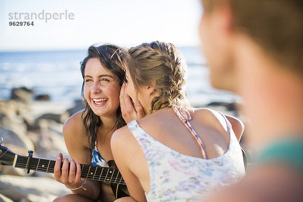 Mädchen teilen ein Geheimnis am Strand