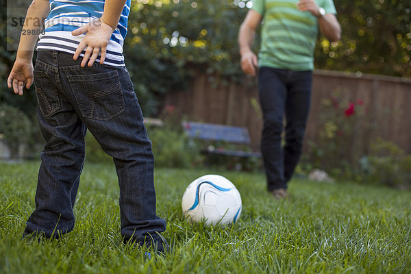 Vater und Sohn spielen Fußball im Garten