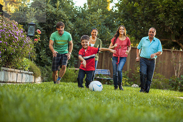 Drei Generationen Familie spielen Fußball im Garten
