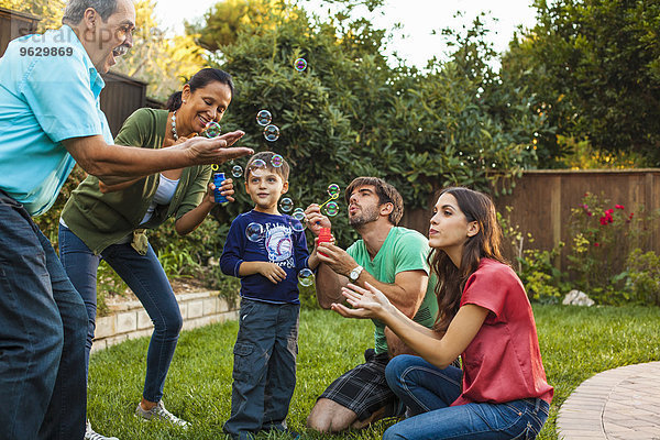 Drei Generationen Familie blasen Blasen im Garten