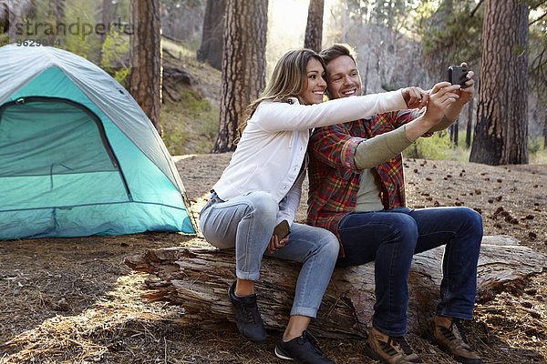 Junges Camping-Pärchen mit Smartphone Selfie im Wald  Los Angeles  Kalifornien  USA