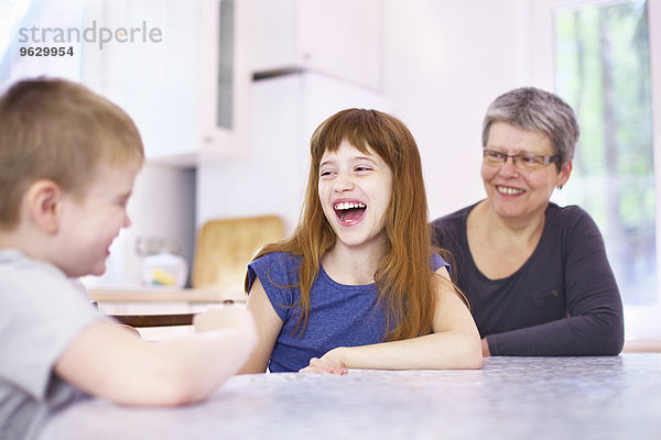 Großmutter und Enkelkinder lachen am Küchentisch