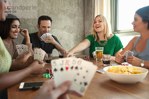 Gruppe von Freunden beim Kartenspielen am Tisch