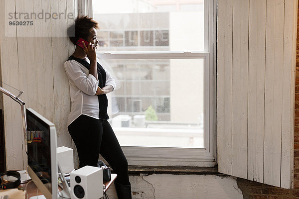 Frau mit Smartphone am Fenster  Home-Office