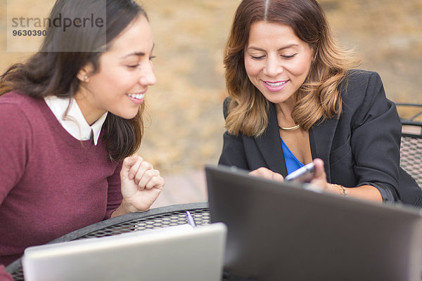 Geschäftsfrauen  die Laptops und Telefone im Freien benutzen