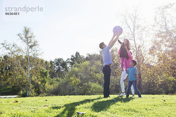 Reife Paare und Kinder beim Fangen mit Ball im Park