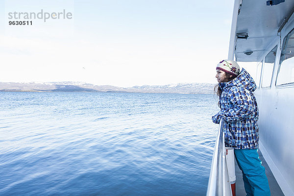 Mädchen lehnt sich gegen das Geländer auf einem Boot  das Richtung Küste segelt  Ushuaia  Feuerland  Argentinien