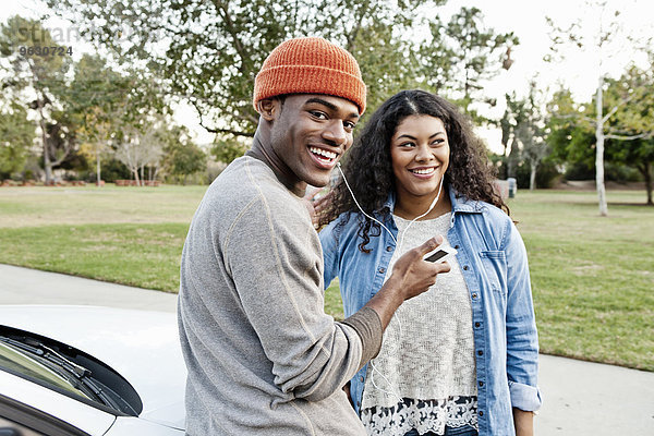 Porträt eines jungen Paares im Parkhaus mit gemeinsamer Smartphone-Musik