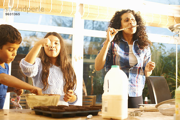 Mutter und Kinder probieren Kuchenmischung in der Küche