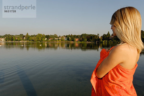 Mittlere erwachsene Frau in Handtuch gewickelt  mit Blick auf den See
