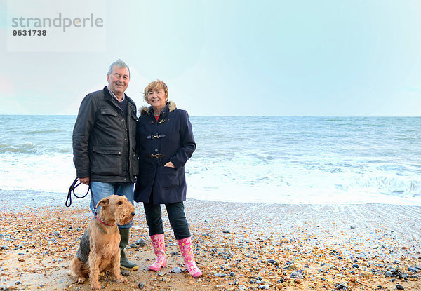 Porträt eines älteren Paares mit Hund am Strand