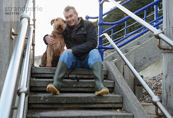 Porträt eines älteren Mannes mit Hund auf einer Treppe sitzend