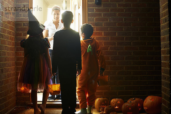 Rückansicht von drei Kindern  die Halloween-Kostüme tragen.