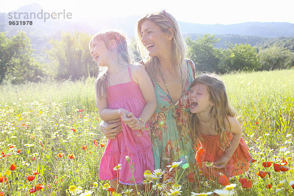 Mittlere erwachsene Frau und zwei Töchter lachend auf einer Wildblumenwiese  Mallorca  Spanien