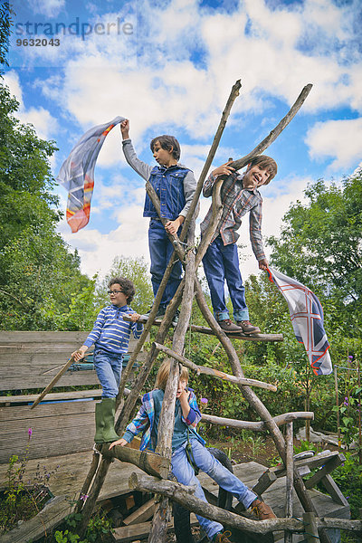 Vier Jungen klettern auf hausgemachtem Klettergerüst im Garten