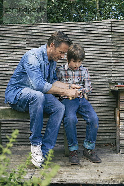 Vater zeigt Sohn  wie man ein Taschenmesser bei der Zuteilung benutzt